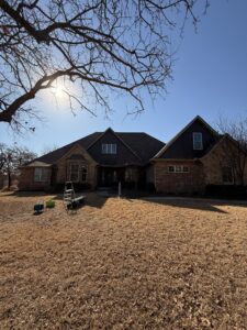 two-story house with bare trees and equipment on the ground indicating potential cleaning or maintenance work being done