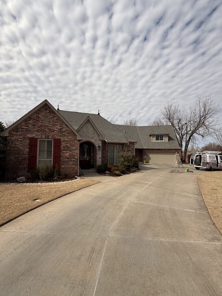 house with a clean driveway and well maintained landscaping observed with a ladder and equipment nearby