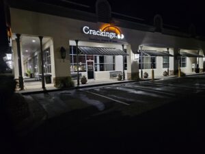 aqua tech pressure washing cleaning a storefront with wet pavement visible and exterior lighting illuminating the area