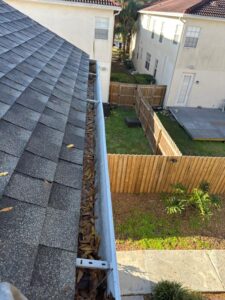 gutter cleaning service removing leaves and debris from a residential gutter system beside the roof of a house