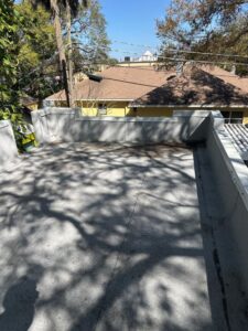 cleaning of a flat rooftop with shadows from surrounding trees and nearby houses visible in the background