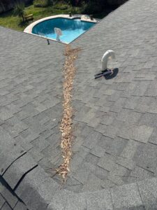 clogged roof valley with leaves and debris near pool indicating need for gutter maintenance and cleaning services