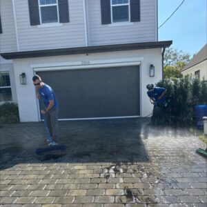 two workers cleaning the driveway using pressure washing techniques and equipment with a focus on surface restoration