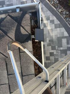 a ladder positioned near a roof edge with leaves and debris along the gutter area possibly for gutter cleaning services