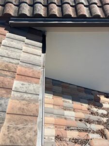 gutter cleaning service showing clean and dirty sections of tiled roof with visible gutter system and debris removal