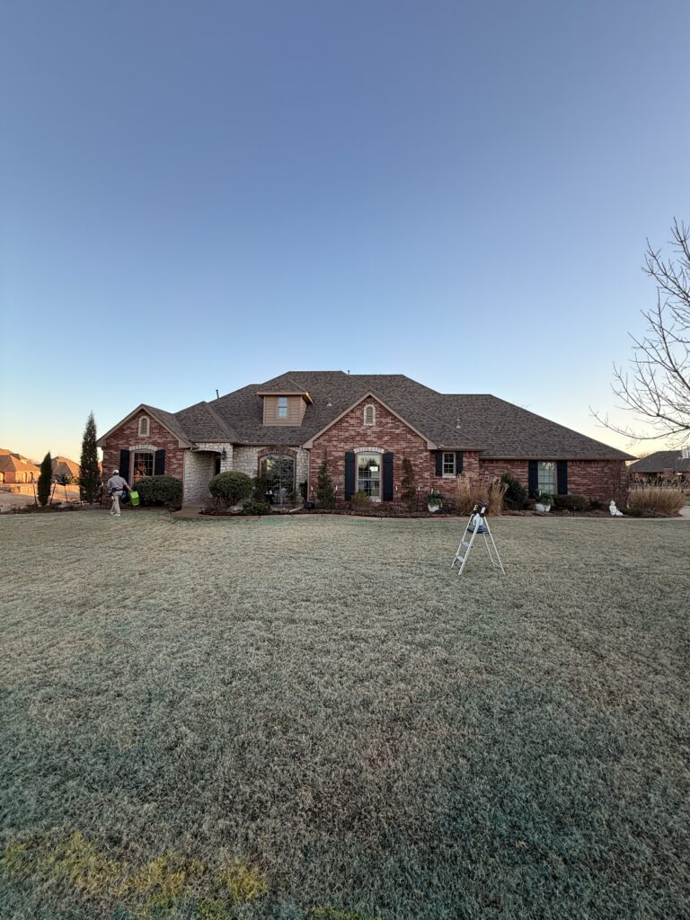 pane fully clean performing exterior cleaning of a house with a ladder and equipment on the lawn and clear sky