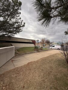 a parking lot with green grass and a building visible nearby a company vehicle is parked in the background