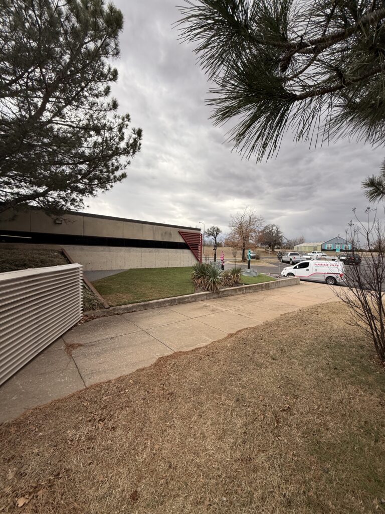 a parking lot with green grass and a building visible nearby a company vehicle is parked in the background