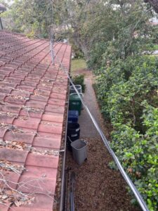 gutter cleaning service removing debris from a roof with terracotta tiles