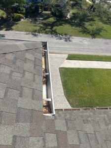gutter cleaning with debris visible in the gutters and a clear view of the roof and surrounding landscape