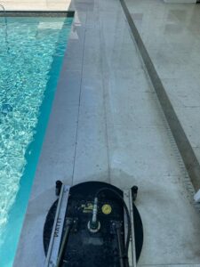 surface cleaning around a swimming pool using a specialized cleaning tool to remove dirt and debris from tiles
