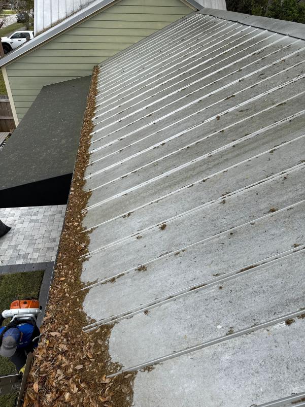 gutter cleaning with leaves and debris removed from a sloped metal roof showing before and after cleaning contrast