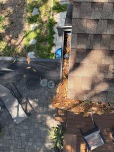 gutter cleaning services in progress with leaves and debris collected on the roof near the gutter system