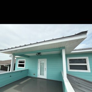 cleaning eaves and inspecting gutters on a light blue house with a modern design and white trim
