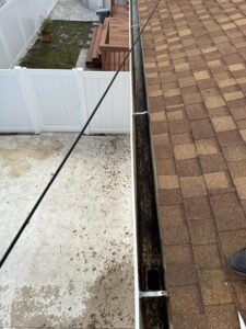 gutter cleaning service in progress with debris visible in the gutters and a view of the roof and surrounding area