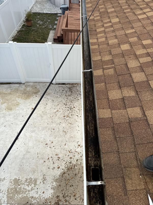 gutter cleaning service in progress with debris visible in the gutters and a view of the roof and surrounding area