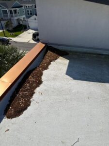 debris removal from a rooftop area with mulch near a metal edge in a residential setting