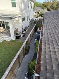 gutter cleaning and maintenance with a view of a landscaped yard and patio area along a residential building