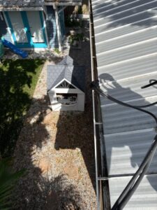rooftop view of a house showing a playhouse and landscaping with a gutter cleaning tool positioned near the edge