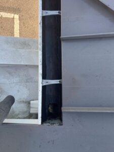 gutter cleaning service using a vacuum to remove debris from a dark gutter system near a roof edge