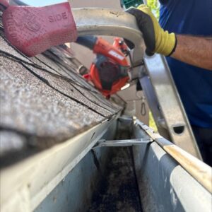 gutter cleaning with a blower removing debris from the gutter system using a ladder for access and safety
