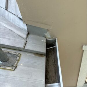 gutter cleaning service focusing on debris removal from a roof drainage area with visible grime and dirt buildup