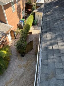gutter inspection from the roof showing a view of the backyard with landscaping and outdoor structure