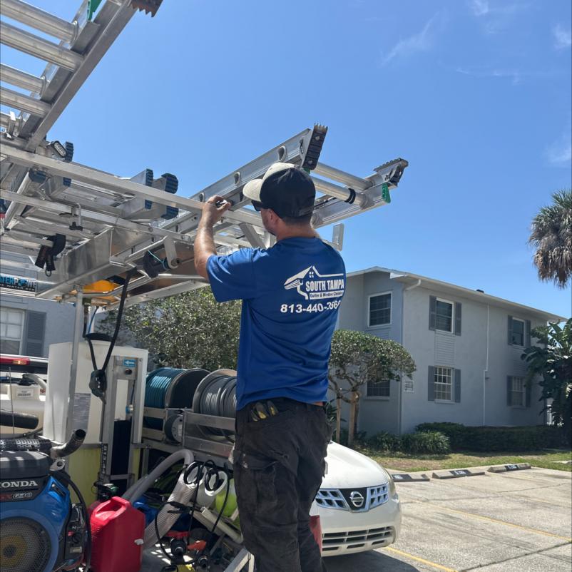 worker adjusting equipment on a truck for gutter and window cleaning services under clear blue sky