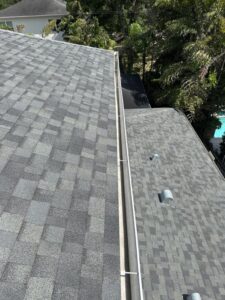 gutter cleaning service being performed on a sloped roof with multiple vent pipes visible
