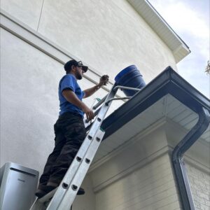 gutter cleaning using a ladder to reach high areas removing debris with a bucket placed on the roof edge