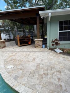 patio cleaning with stone pavers near a pool and a covered seating area with plants and furniture visible