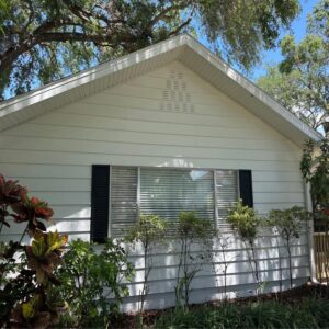house washing white vinyl siding with clean windows and well-manicured shrubs and plants flanking the side of the house
