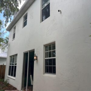 residential house with white textured exterior and windows clean and intact no visible signs of damage or maintenance work