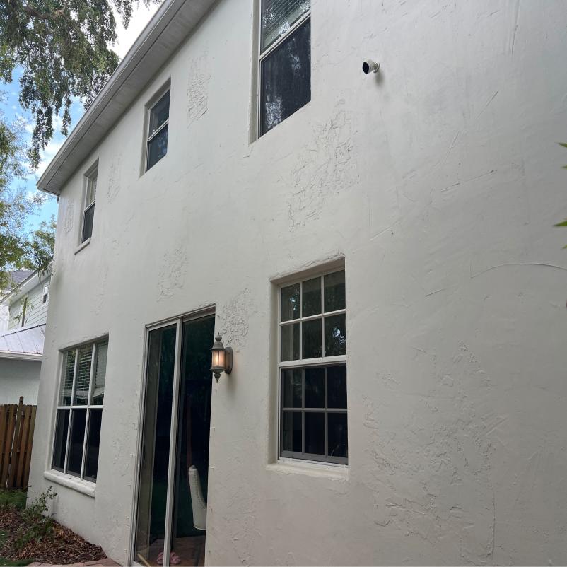 residential house with white textured exterior and windows clean and intact no visible signs of damage or maintenance work