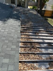 leaves and debris accumulating on a roof indicating potential gutter cleaning services needed