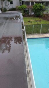 gutter cleaning service showing debris collected on a rooftop adjacent to a swimming pool with clear water
