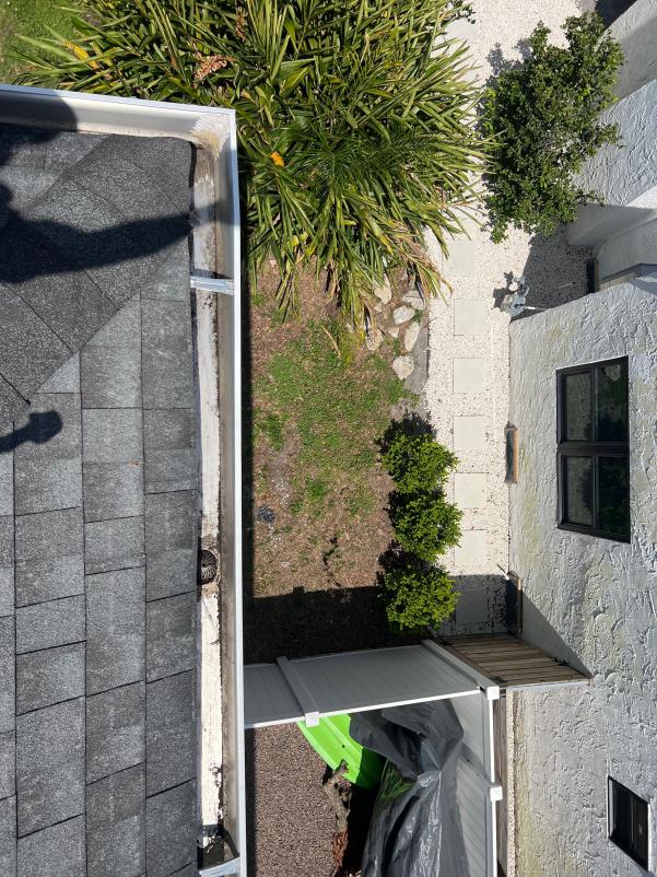gutter cleaning service with a view of a roofline and landscaping in a residential area