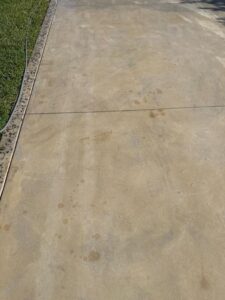 concrete surface cleaning revealing stains and dirt on a driveway needing pressure washing services