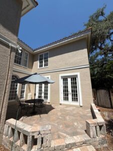 hardscaping and patio cleaning with outdoor furniture and umbrella near a well-maintained house and clear blue sky