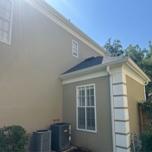 gutter cleaning service with a clear blue sky and well-maintained home exterior