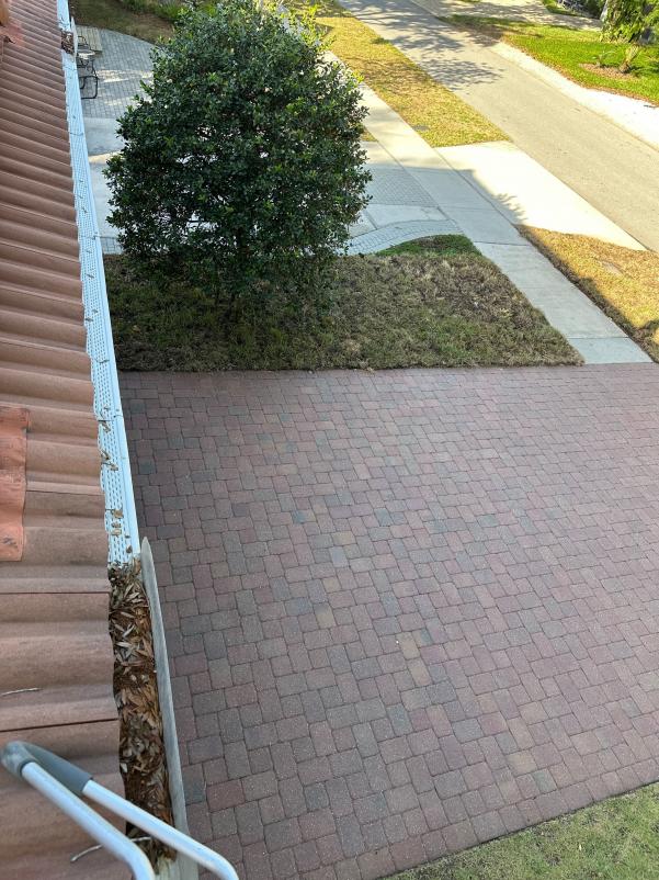 cleaning of a paver driveway with some debris visible along the edge of the walkway and grass area