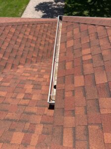 gutter cleaning service being performed on a sloped roof with red shingles and visible debris in the gutters