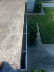 gutter cleaning service showing debris and leaves collected in the gutter with a clear view of the surrounding yard