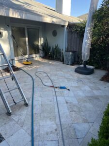pressure washing a stone patio with hoses and a pressure washer in a residential outdoor space