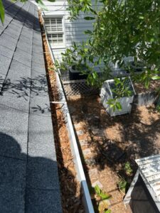 gutter cleaning service with debris visible in the gutter and a clear view of the surrounding area and landscaping