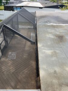 gutter cleaning service showing dirt accumulation on a roof and wooden deck area with visible debris and a covered patio