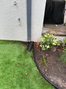 drainage system installation with downspout directing water away from building and landscaping features nearby