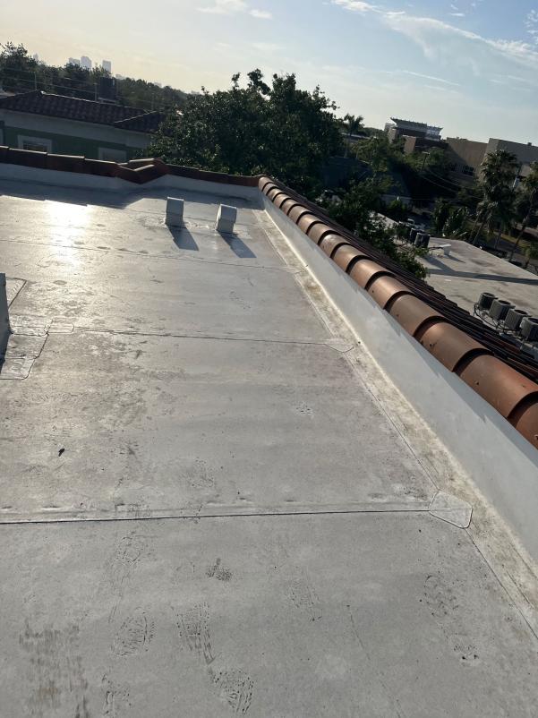 roof cleaning service with a flat surface and visible footprints near tiled edge and HVAC units in background