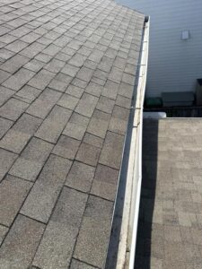 roof inspection showing shingles and gutters with some debris accumulation and signs of wear or damage