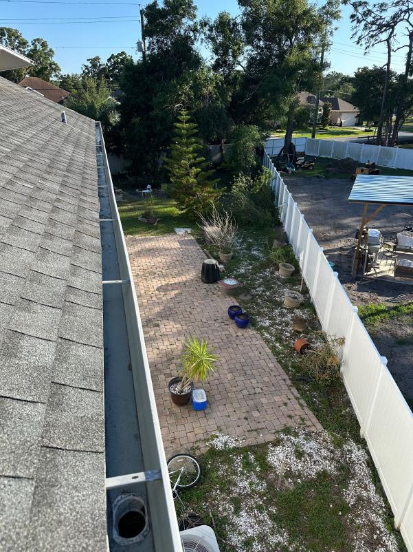 gutter cleaning service with a view of a backyard patio and surrounding greenery and landscaping features